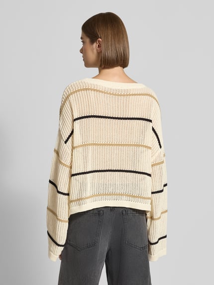 Frauenmodel trägt Oversized Strickpullover mit Label-Detail und Rundhalsausschnitt von Karo Kauer, grober cremefarbener Strick mit schwarzem Streifenmuster, Rückenlänge bei Größe S 55 cm, Ärmellänge 76 cm, Ganzkörperansicht Rückansicht.