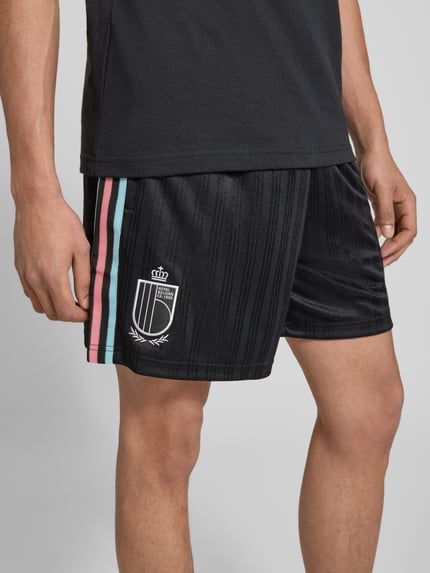 Männermodel trägt Regular Fit Sweatpants mit Label-Detail Modell 'Belgien 26' van adidas Originals, zwart, effen, zijdelingse steekzakken, elastische tailleband, sweatmateriaal, detailopname van het bovenbeen