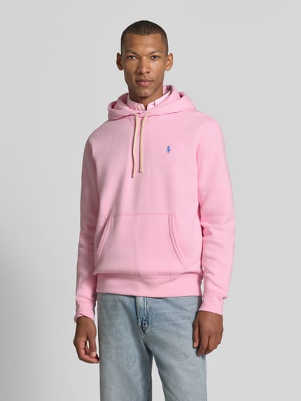 Männermodel trägt Regular Fit Hoodie aus Baumwoll-Mix von Polo Ralph Lauren in Rosa mit Kängurutasche, Jeans, Ganzkörperansicht von vorne. Herren Hoodie von Polo Ralph Lauren