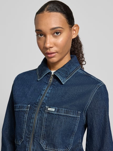 Vrouwenmodel draagt Cropped Jeansjacke mit Reißverschluss van GUESS, donkerblauw, mix van katoen en elastaan, platte kraag, borstzakken, Nahaufnahme bovenlichaam.