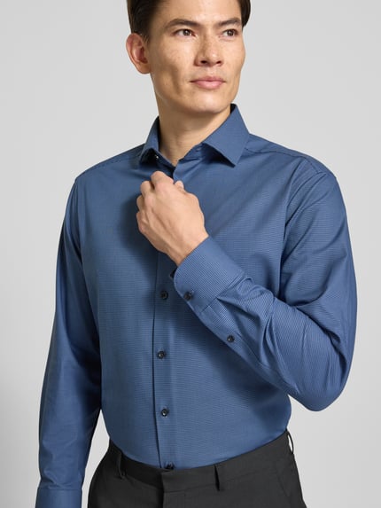 Männermodel trägt Regular Fit Businesshemd mit Kentkragen von OLYMP, unifarben, matt, feines Webmuster, Nahaufnahme Oberkörper.