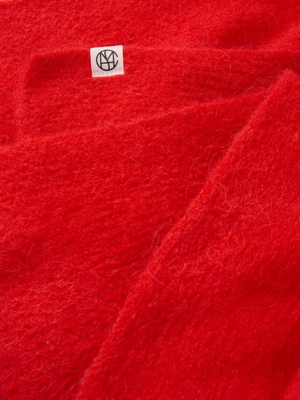 Produktfoto, Schal aus elastischem Woll-Mix mit Alpaka-Anteil Modell 'Hope' von MSCH Copenhagen, rechteckig, leuchtend rot, flauschige Textur, Label-Detail sichtbar, 41 cm breit und 105 cm lang