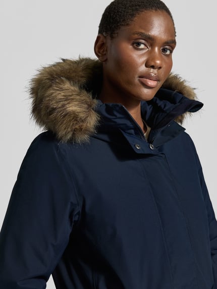 Frauenmodel trägt Regular Fit Parka mit Kunstfellbesatz Modell 'ERNA' von Didriksons in Dunkelblau, Nahaufnahme Oberkörper. Damen Parka mit Thermore Füllung, 10.000mm Wassersäule, Kapuze, Rückenlänge 93 cm, Schulterbreite 42 cm, Brustweite 51 cm, Ärmellänge 66 cm.