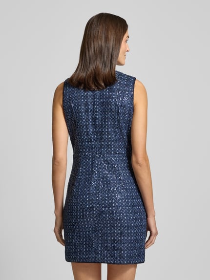 Frauenmodel trägt Minikleid mit Allover-Pailettenbesatz Modell 'Gabriela' von Guess in Dunkelblau, taillierte Passform, Ganzkörperansicht Rückansicht.
