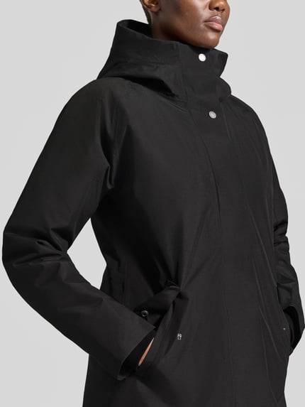 Frauenmodel trägt Regular Fit Parka mit Kapuze Modell 'Alana' von Didriksons in Schwarz, glatte Oberfläche, Nahaufnahme Oberkörper. Damen Parka von Didriksons, Eingrifftaschen, Rückenlänge 90 cm, Schulterbreite 38 cm, Brustweite 48 cm, Ärmellänge 74 cm.