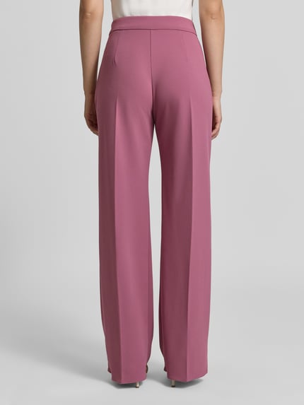 Vrouwenmodel draagt Straight Fit Stoffhose met Bügelfalten van Rinascimento, Materiaalmix met stretch, elastische band, steekzakken, persplooien, bandwijdte maat S 37 cm, binnenbeenlengte maat S 82 cm, roze tint, gladde textuur, Ganzkörperansicht Rückansicht.