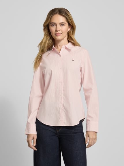 Vrouwenmodel draagt Regular Fit Hemdbluse aus Baumwoll-Mix van Tommy Hilfiger, lichtroze met allover patroon, popeline, knoopsluiting, logo detail, langemouwen, afgeronde zoom, vooraanzicht van het hele lichaam.