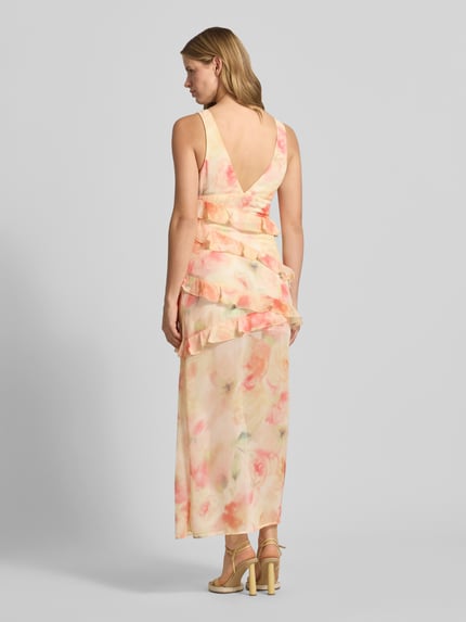 Vrouwenmodel draagt maxi-jurk met ruches van Gina Tricot, nauwsluitend, all-over bloemenprint, mouwloos design, loopsplit. Ganzkörperansicht Rückansicht.