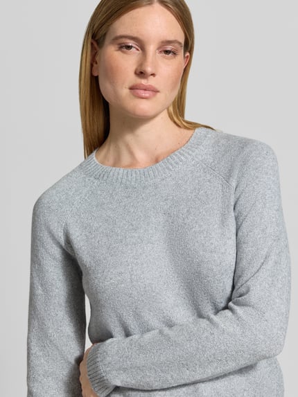 Frauenmodel trägt Pullover mit strickartiger Struktur in Hellgrau, Regular Fit von VERO MODA, Rundhals, Langarm, Nahaufnahme Oberkörper.