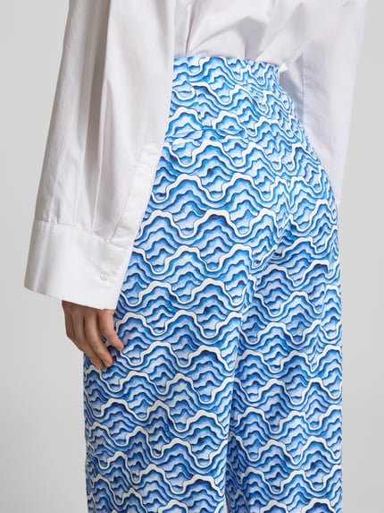 Vrouwenmodel draagt Wide Fit Stoffhose mit elastischem Bund van HERZENS, blauw-wit golvend patroon, detailopname rug, elastische mix, achterzakken, taillewijdte maat 36: 35 cm, binnenbeenlengte maat 36: 78 cm.