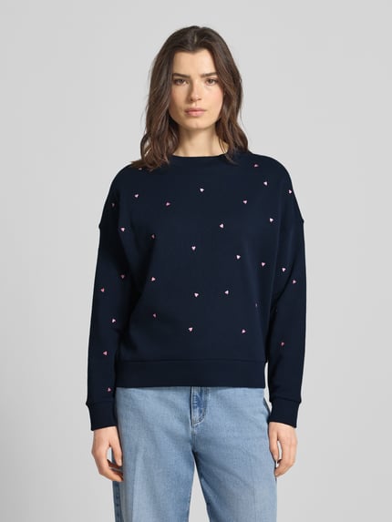 Vrouwenmodel draagt Regular Fit Sweatshirt uit pure katoen van Tom Tailor Denim, effen donkerblauw met allover borduursel, crew neck, lange mouw, geribde boorden, sweatmateriaal, frontale full-body opname.