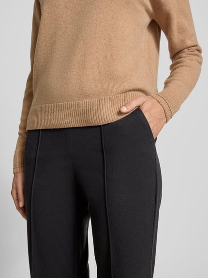 Vrouwenmodel draagt Flared Stoffhose met fixierten Bügelfalten van Christian Berg Woman, materiaalmix met viscose, persplooien, paspelzakken, zwarte kleur, flared cut, detailopname heup en bovenbenen.