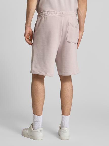Männermodel trägt Loose Fit Sweatshorts aus reiner Baumwolle Modell 'Nomario' von Hugo Blue, Optik: Unifarben, Sweat, Ganzkörperansicht Rückansicht.