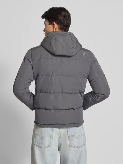 Männermodel trägt graue Steppjacke mit Kapuze, Eingrifftaschen und Label-Detail, Modell 'Everest' von Superdry, Regular-Fit, Ganzkörperansicht Rückansicht, Rückenlänge 66 cm, Schulterbreite 48 cm, Brustweite 42 cm, Ärmellänge 70 cm, Größe M.