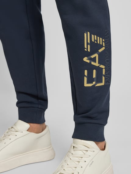 Männermodel trägt Sweatpants mit elastischem Bund und Label-Print von EA7 Emporio Armani, Reine Baumwolle, Dunkelblau, Nahaufnahme Unterbein.