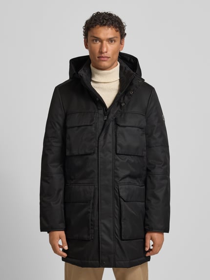 Männermodel trägt Jacke mit Pattentaschen Modell von NAUTGÅRD, Regular-Fit, Kapuze, Schwarz, Größe M, Ganzkörperansicht von vorne.