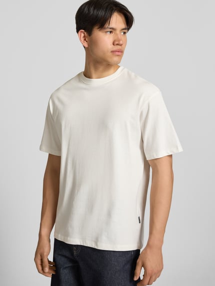 Männermodel trägt Oversized T-Shirt Modell 'FISHER' von Blend aus reiner Baumwolle in Weiß, Rundhalsausschnitt, Ganzkörperansicht von vorne.