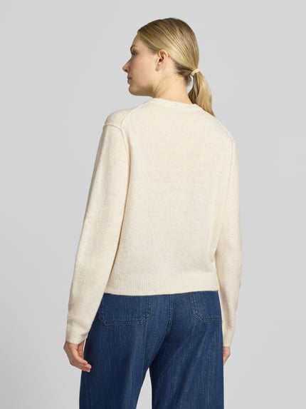 Frauenmodel trägt Strickjacke mit Rundhalsausschnitt und Knopfleiste von Oui, feine Woll-Textur, cremefarben, Regular Fit, Rückenansicht.