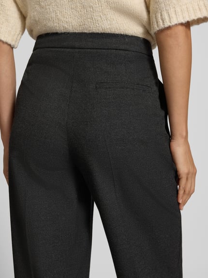 Frauenmodel trägt Regular Fit Jogpants mit Bundfalten von MARC O'POLO in Melange-Optik, feines Webmuster, Nahaufnahme Rückansicht.