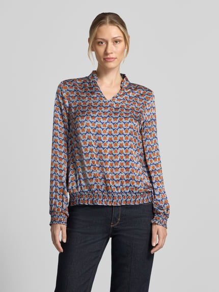 Frauenmodel trägt Regular Fit Bluse aus reiner Viskose von MORE & MORE mit grafischem Muster, Stehkragen, Langarm, Ganzkörperansicht von vorne.