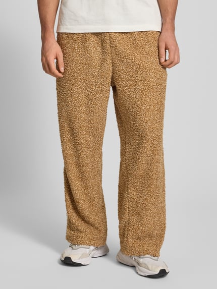 Männermodel draagt Jogpants uit teddybont met labelstitching van adidas Originals, regular fit, steekzakken, elastische band, binnenbeenlengte maat M 43 cm, Ganzkörperansicht van voren.