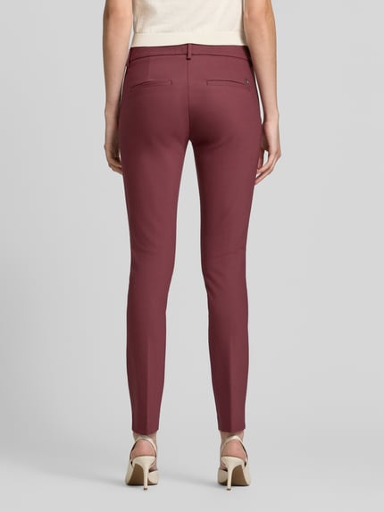 Frauenmodel trägt Slim Fit Anzughose aus Baumwoll-Mix von MOS MOSH, Farbe bordeaux, angedeutete kieszenie z tyłu, szlufki, zapięcie na guzik i zamek błyskawiczny, Szerokość w rozmiarze 36: 39 cm, Długość wewnętrzna nogawki w rozmiarze 36: 76 cm, Ganzkörperansicht Rückansicht