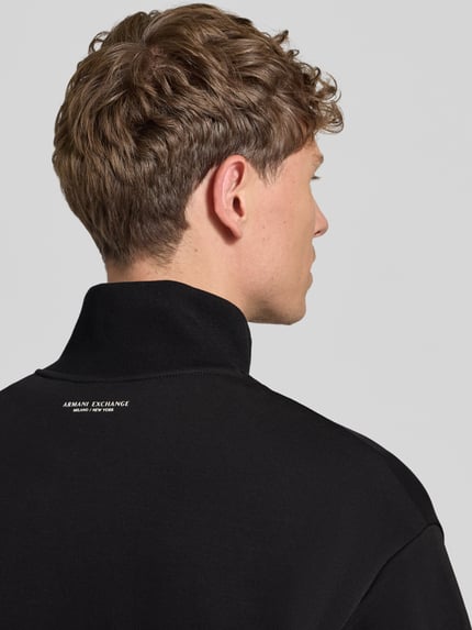 Mężczyznamodel nosi Sweatjacke aus Baumwoll-Mix od Armani Exchange, czarny kolor, nadruk z logo, ściągacze, luźny krój, widok na plecy, zdjęcie w ujęciu z tyłu.