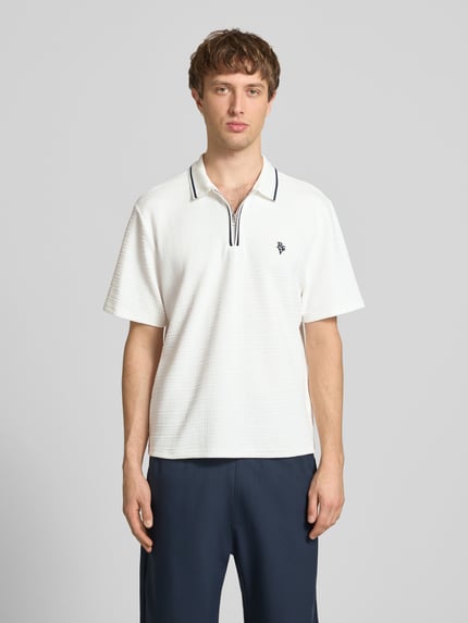 Männermodel trägt Regular Fit Poloshirt mit Reißverschluss und Label-Stitching von REVIEW, Material-Mix, Strukturmuster, Ganzkörperansicht von vorne.