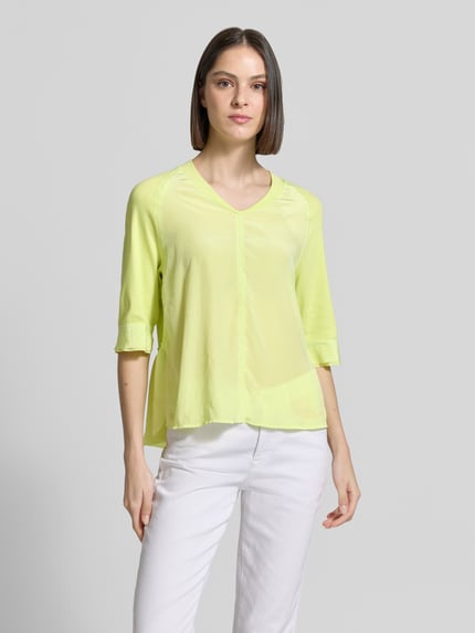 Frauenmodel trägt T-Shirt mit V-Ausschnitt und 3/4-Arm von Marc Cain in Gelb, Relaxed-Fit, Baumwoll-Elasthan-Mix, Rückenlänge 60 cm, Ganzkörperansicht von vorne.