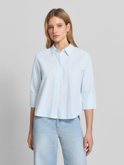 Frauenmodel trägt Regular Fit Hemdbluse aus Lyocell-Baumwoll-Mix von Tom Tailor, gestreifte Popeline, hellblaue Farbe, Ganzkörperansicht von vorne.