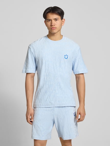 Męski model nosi Regular Fit T-Shirt aus Frottee od Hugo Blue w kolorze niebieskim, efekt: jednolity kolor, okrągły dekolt, krótki rękaw, wykończenie materiału: frota, materiał: czysta bawełna, widok całej sylwetki z przodu