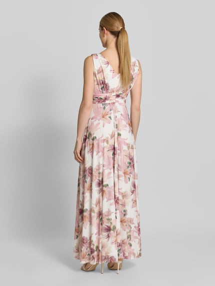 Frauenmodel trägt Maxikleid mit V-Ausschnitt und Gehschlitz von Christian Berg Cocktail, floraler Allover-Look in Rosa und Creme, Material-Mix mit Stretch, A-Linie, Ganzkörperansicht Rückansicht.