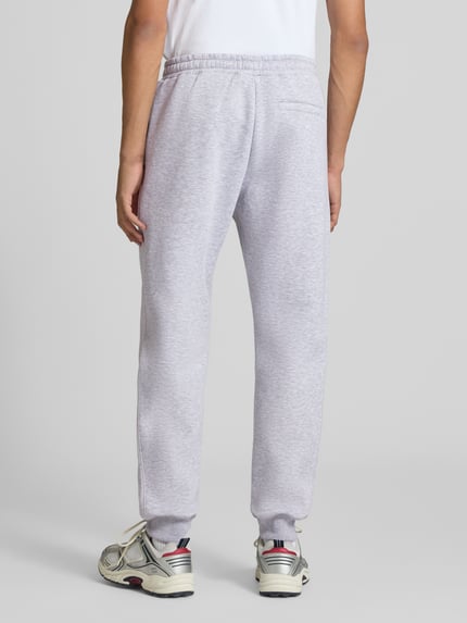 Männermodel trägt Slim Fit Sweatpants mit Tunnelzug von REVIEW in Hellgrau, elastischer Bund, Gesäßtasche, Ganzkörperansicht Rückansicht.
