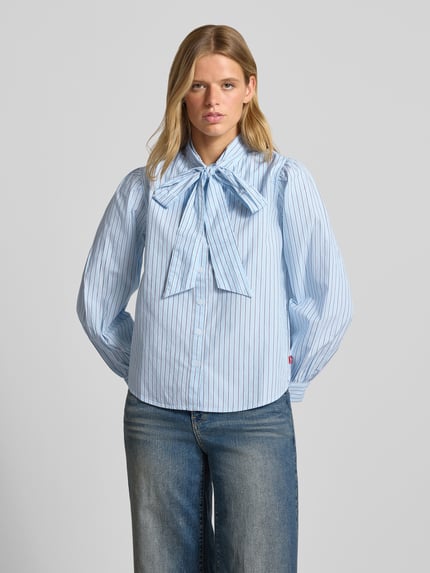 Frauenmodel trägt Regular Fit Langarmbluse aus reiner Baumwolle von Levi's® 300, hellblau mit feinen Streifen, lockere Passform, Ganzkörperansicht von vorne.