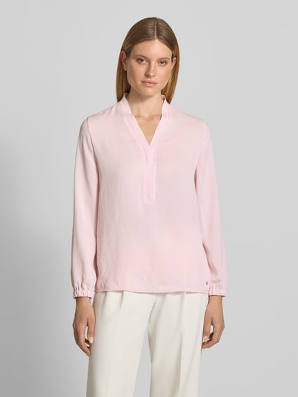 Modelka prezentuje Regular Fit Bluse mit V-Ausschnitt von Marc Cain, jasnoróżowa bluzka, krój regular fit, dekolt w serek, detal z logo, długość tyłu w rozmiarze 36: 65 cm, długość rękawów w rozmiarze 36: 59 cm, widok całej sylwetki z przodu