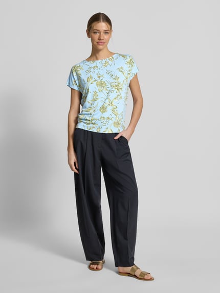 Frauenmodel trägt Relaxed Fit T-Shirt aus weichem Viskose-Mix von s.Oliver RED LABEL mit Optik:Allover-Muster, florales Muster, U-Boot-Ausschnitt, Kurzarm, in zarten Pastellfarben, Ganzkörperansicht von vorne.