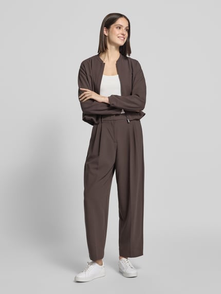 Frauenmodel trägt Blouson mit Viskose-Anteil von COMMA in Dunkelbraun, lockere Passform, Stehkragen, elastische Abschlüsse, Ganzkörperansicht von vorne.