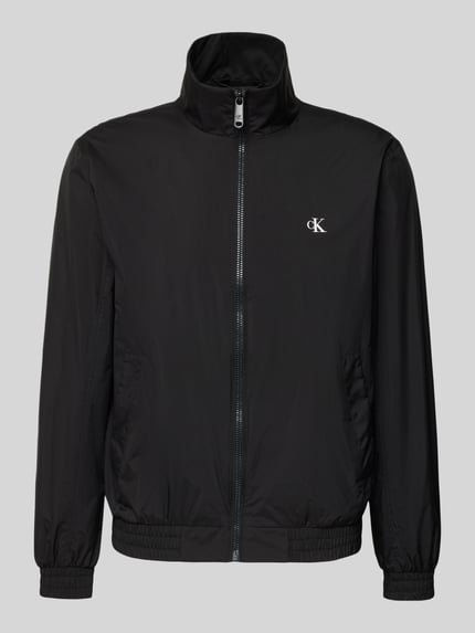 Produktfoto, schwarze Trainingsjacke mit Logo und Stehkragen von Calvin Klein Jeans, sichtbarer Reißverschluss, seitliche Eingrifftaschen, glatte Oberfläche