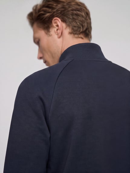 Männermodel trägt Sweatshirt mit Logo-Schriftzug Troyer von BOSS in Dunkelblau, strukturierte Jersey-Optik, Ganzkörperansicht Rückansicht.