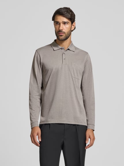 Męski model nosi Regular Fit Poloshirt aus Baumwoll-Mix od RAGMAN, bawełniana mieszanka, krój regular fit, kieszeń na piersi, elastyczne wykończenia, długi rękaw, długość tyłu w rozmiarze M: 70 cm, widok całej sylwetki z przodu.