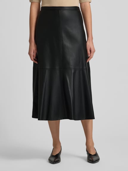 Frauenmodel trägt Midirock in Leder-Optik Modell 'PARIS' von Mango, lockerer Schnitt, Nahtreißverschluss, schwarze Oberfläche, Ganzkörperansicht von vorne.
