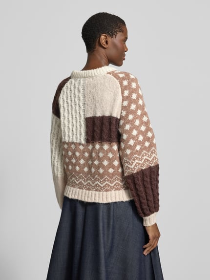 Frauenmodel trägt Pullover mit Strukturmix von VERO MODA in Creme und Braun mit Patchwork-Optik, Zopfmuster und Punkten, Ganzkörperansicht Rückansicht.