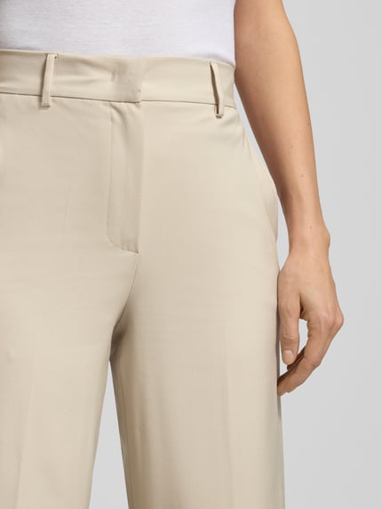 Männermodel trägt Wide Leg Bundfaltenhose aus reiner Schurwolle Modell 'CORONE' von Weekend Max Mara, gładka, kremowa tkanina, wysoki stan, szerokie nogawki, label stitching, szlufki, zapięcie na haftkę i ukryty zamek, boczne kieszenie, webowa wełna, Nahaufnahme Oberkörper.