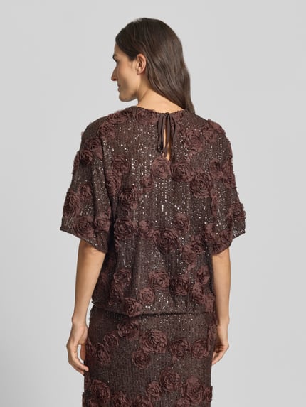 Frauenmodel trägt Blusenshirt mit Pailletten Modell 'ELYSIA' von YAS in Braun, Material-Mix mit Stretch, Relaxed Fit, Ganzkörperansicht Rückansicht.