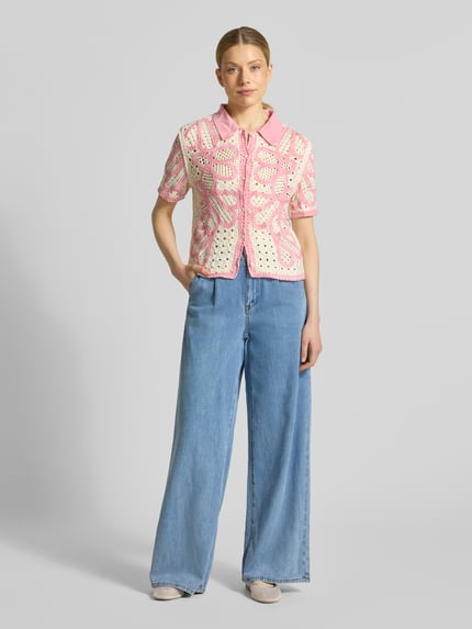 Frauenmodel trägt Jeans mit elastischem Bund und Eingrifftaschen Modell 'RUDY' von SUNCOO PARIS, Lyocell-Baumwoll-Mix, Wide Leg, helle blaue Farbe, glatte Textur, kombiniert mit gehäkeltem rosa-beigem Oberteil, Ganzkörperansicht von vorne.