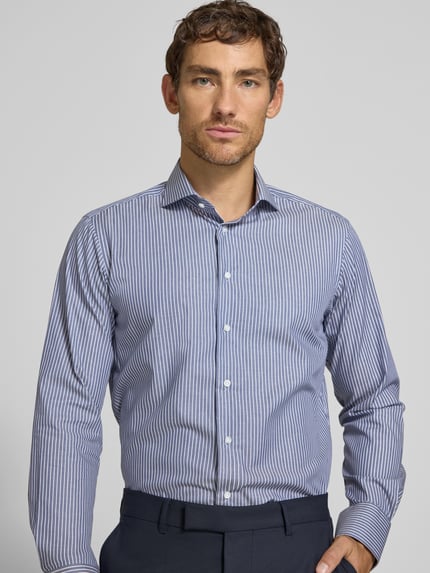 Männermodel trägt Regular Fit Business-Hemd aus Baumwolle von Christian Berg Men, blau-weiß gestreift, Haifischkragen, Nahaufnahme Oberkörper.