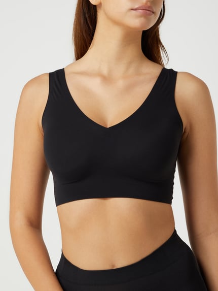 Kobiece modelka nosi czarny Bustier mit Stretch-Anteil Modell 'INVISIBLE SOFT' od Schiesser, elastyczny materiał, dopasowany krój, V-dekolt, wzmocnione i wyjmowane miseczki, szeroka guma, zbliżenie na górną część ciała z przodu.