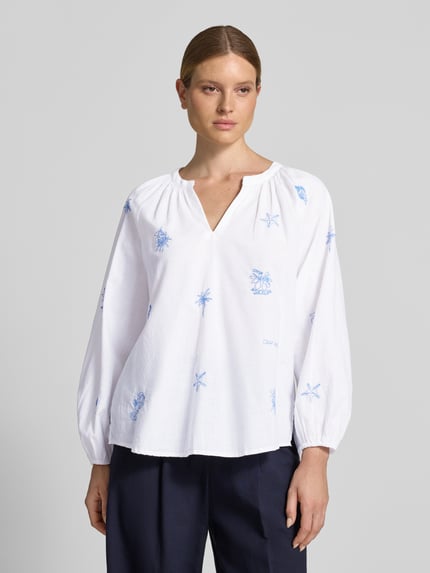 Frauenmodel trägt Regular Fit Tunikabluse mit Stitchings und V-Ausschnitt von Oui aus Reine Baumwolle in Weiß mit blauen Stickereien, Ganzkörperansicht von vorne. Rückenlänge bei Größe 36: 66 cm, Ärmellänge: 59 cm.