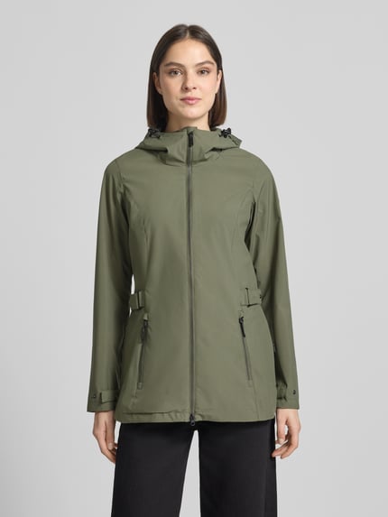 Frauenmodel trägt Regular Fit Regenmantel mit Logo-Detail von G.I.G.A. DX in Olivgrün, Zweiwege-Reißverschluss, Kapuze mit Tunnelzug, Eingrifftaschen; Rückenlänge 76 cm, Schulterbreite 40 cm, Brustweite 50 cm, Ärmellänge 66 cm; Ganzkörperansicht von vorne.
