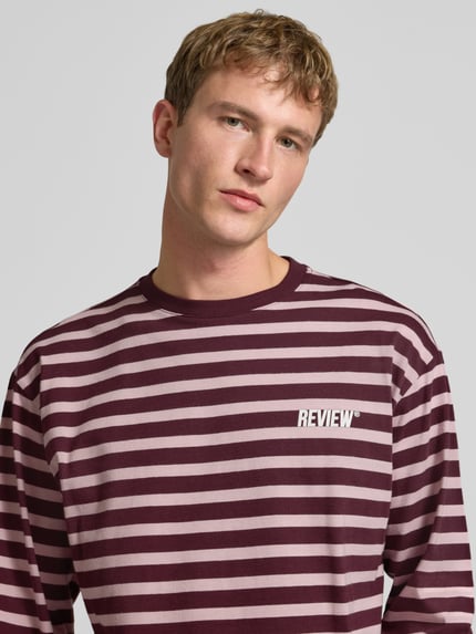 Männermodel trägt Gestreiftes Langarmshirt mit Logoprint vorne und hinten von REVIEW aus reiner Baumwolle, Nahaufnahme Oberkörper.